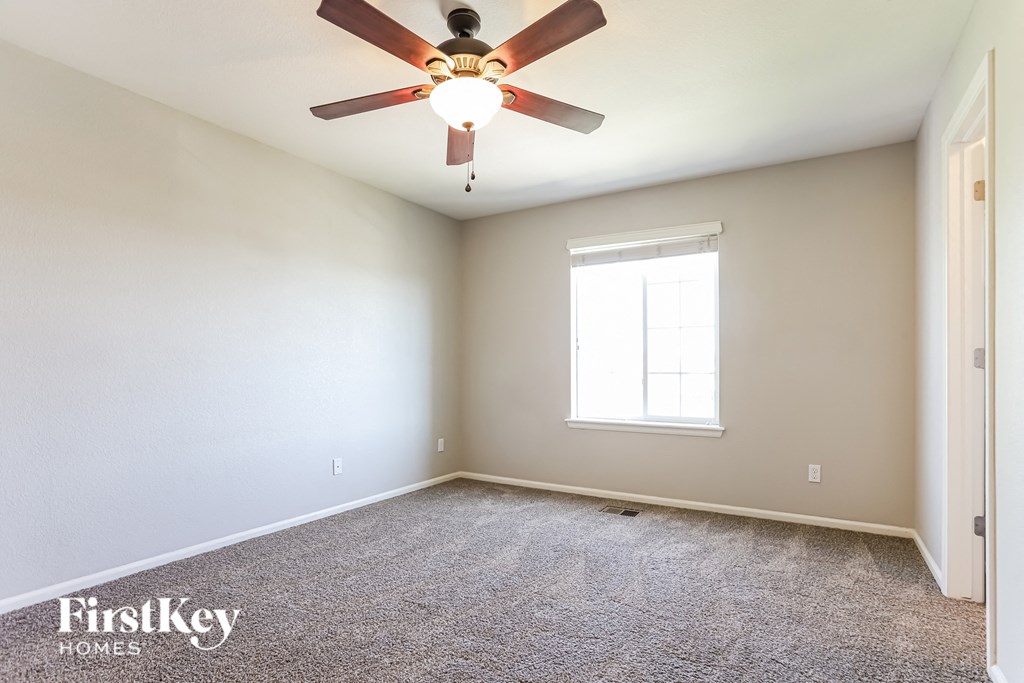 an empty room with a ceiling fan and a window