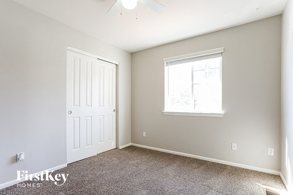 a bedroom with carpeted flooring and a white door and window