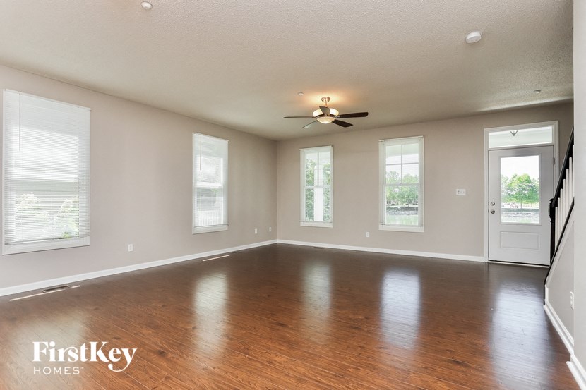 an empty living room with wood floors and a ceiling fan