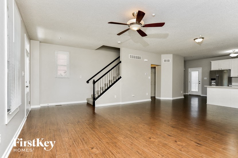 an empty living room with a ceiling fan and a staircase
