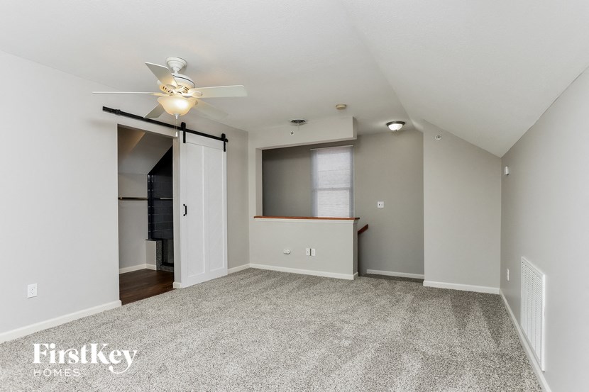an empty living room with a ceiling fan and a closet