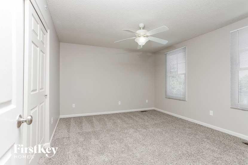 an empty living room with a ceiling fan and a window