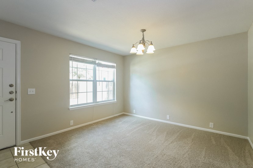 A room with a carpet floor, a door, a window, and a chandelier.