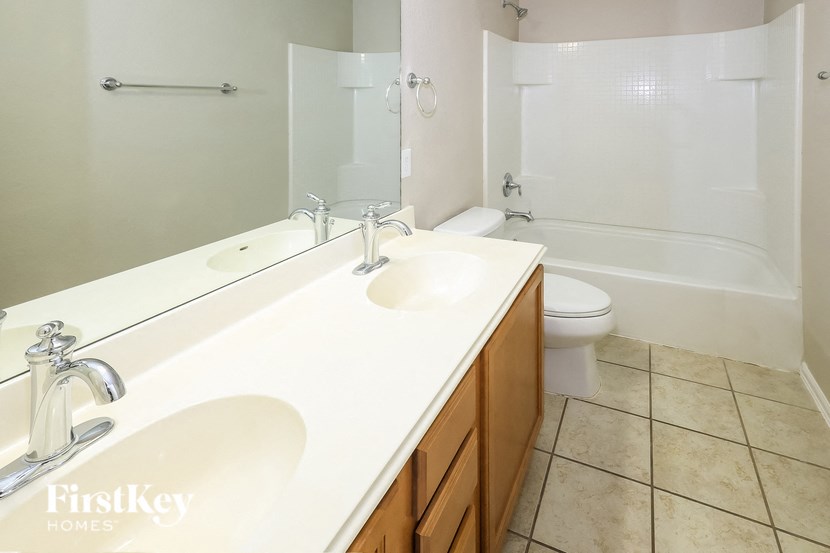 A white bathroom with a double sink and a toilet.