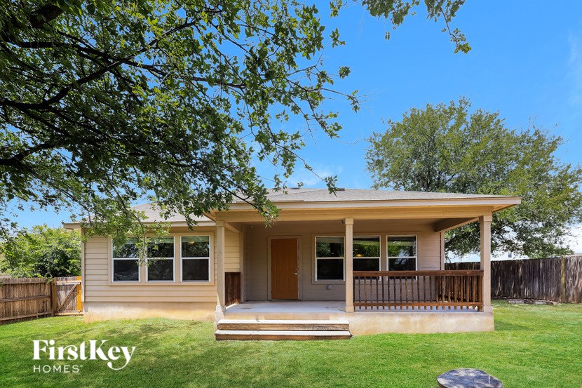 A house with a porch and a tree in the foreground.