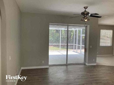 an empty living room with a ceiling fan and sliding glass doors