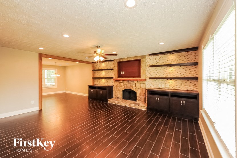 a living room with a stone fireplace and wooden floors