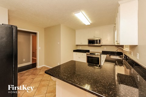 a kitchen with black granite counter tops and white cabinets