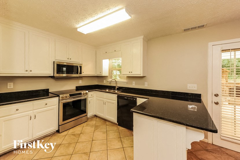 a kitchen with white cabinets and black counter tops