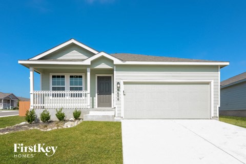 a white house with a garage door and a lawn