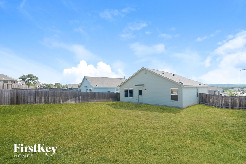 a backyard with a white house and a grassy field