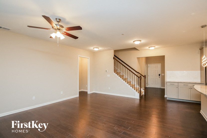 an empty living room with a ceiling fan and a staircase