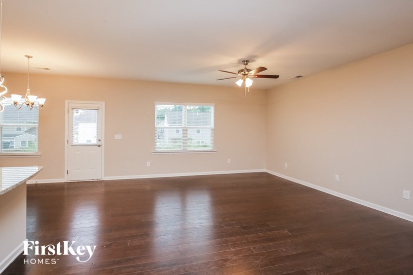 an empty living room with wood floors and a ceiling fan