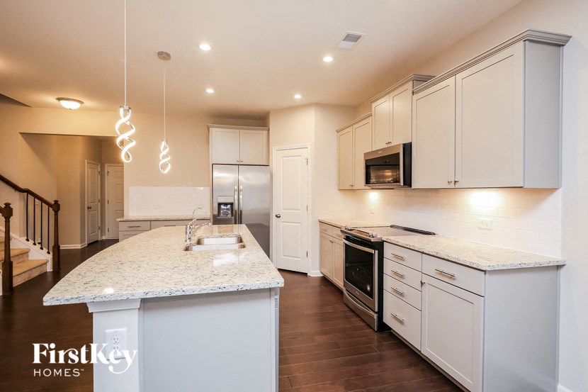 a kitchen with white cabinets and a marble counter top