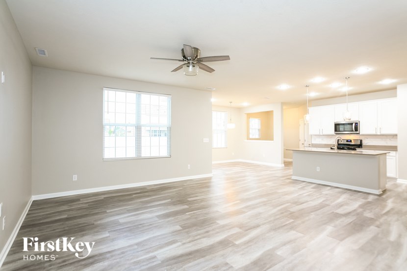 an empty living room and kitchen with a ceiling fan