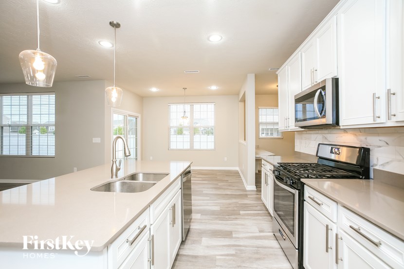 a kitchen with white cabinets and a sink and a stove