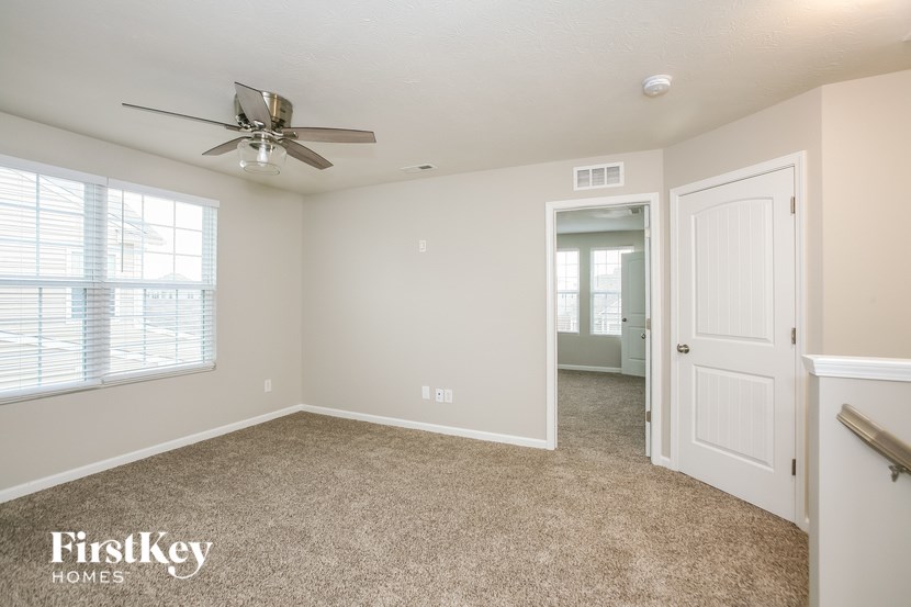 a bedroom with a ceiling fan and a door to a hallway