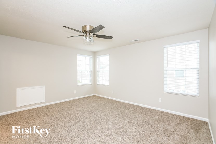 an empty room with a ceiling fan and two windows