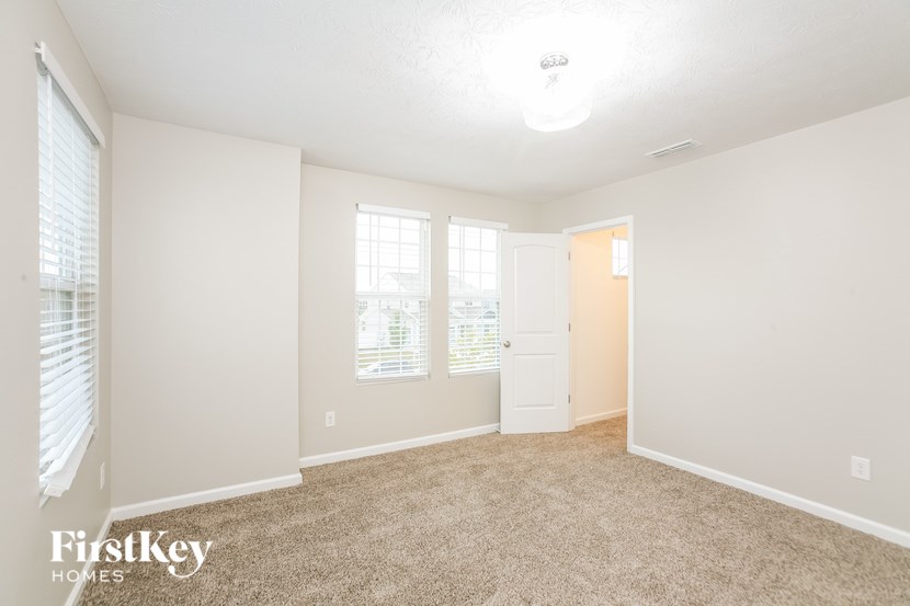 a spacious living room with carpeted flooring and a white door and window