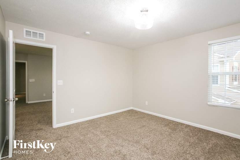 a spacious bedroom with carpeted flooring and a door to the bathroom