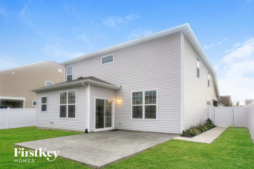 the exterior of a white house with a driveway and grass