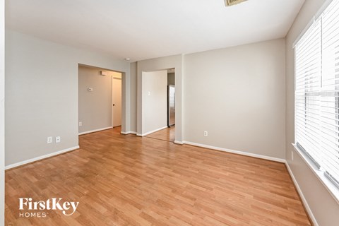 an empty living room with wood flooring and a large window