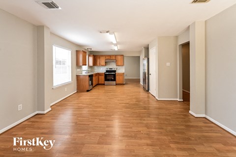 an empty living room and kitchen with wood flooring