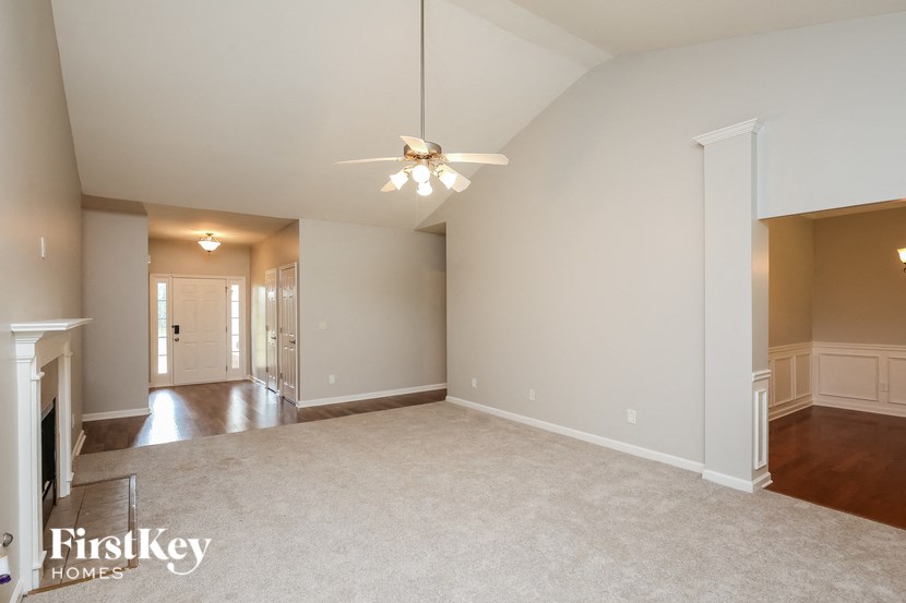an empty living room and dining room with a ceiling fan