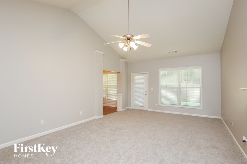 an empty living room with a ceiling fan and a window