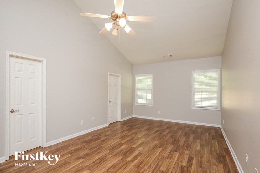 an empty living room with wood flooring and a ceiling fan
