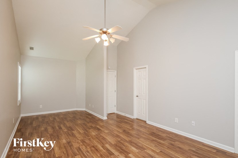 an empty living room with wood flooring and a ceiling fan