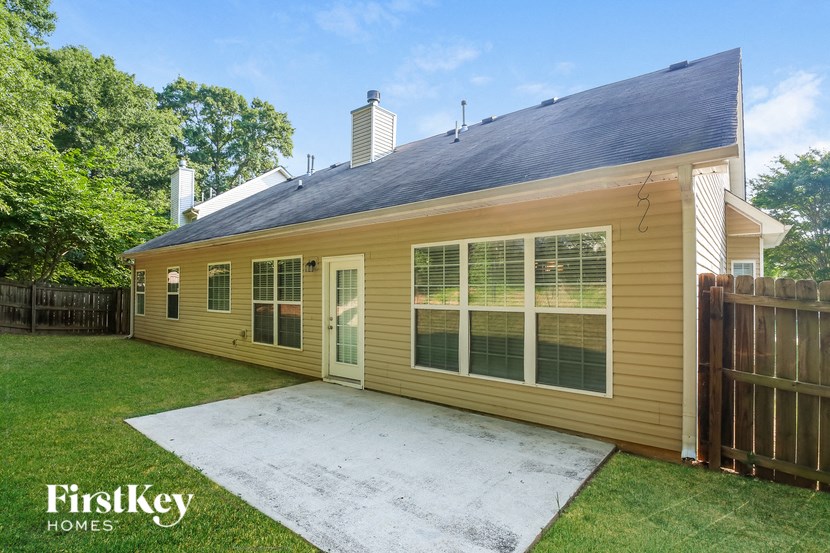 the backyard of a yellow house with a concrete patio