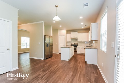 A kitchen with white cabinets and a wooden floor.