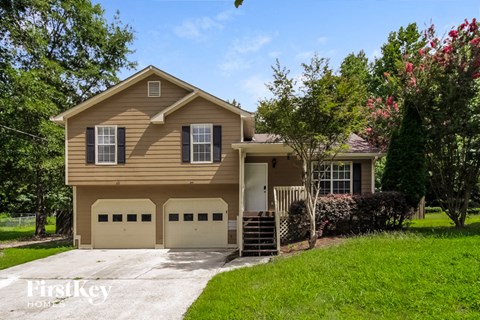 a tan house with two garage doors and a driveway