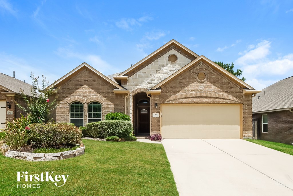 A house with a garage and a driveway in front of it.