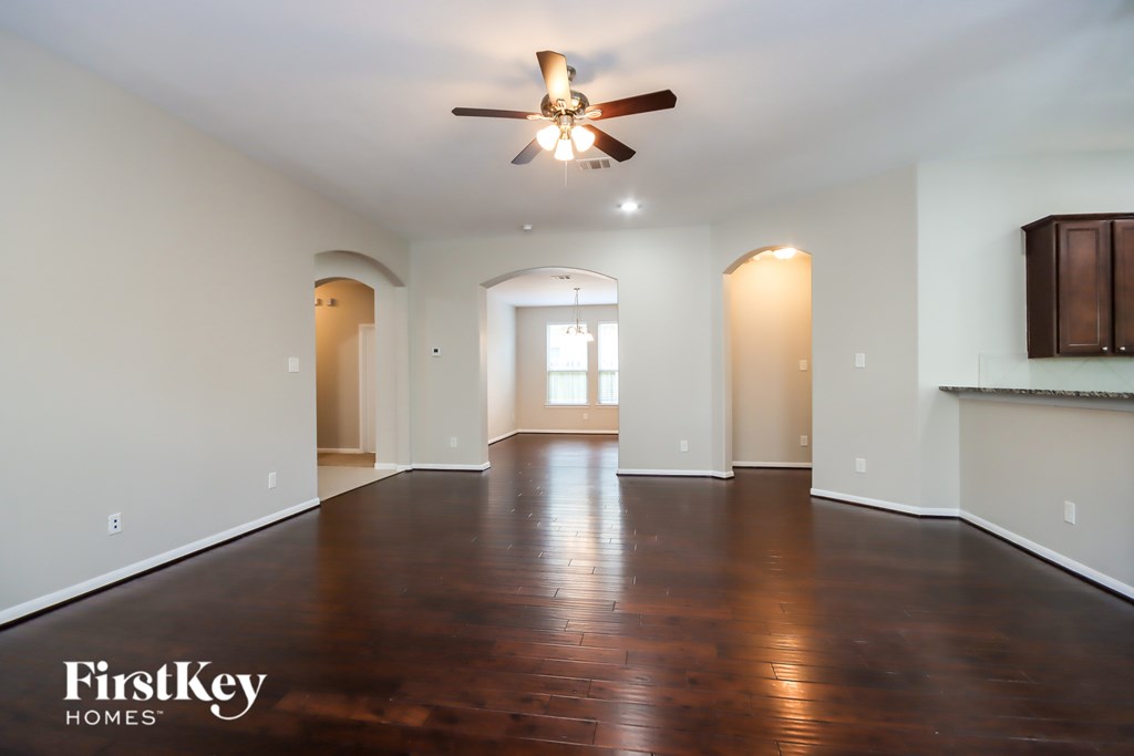 A spacious room with a ceiling fan and wooden flooring.