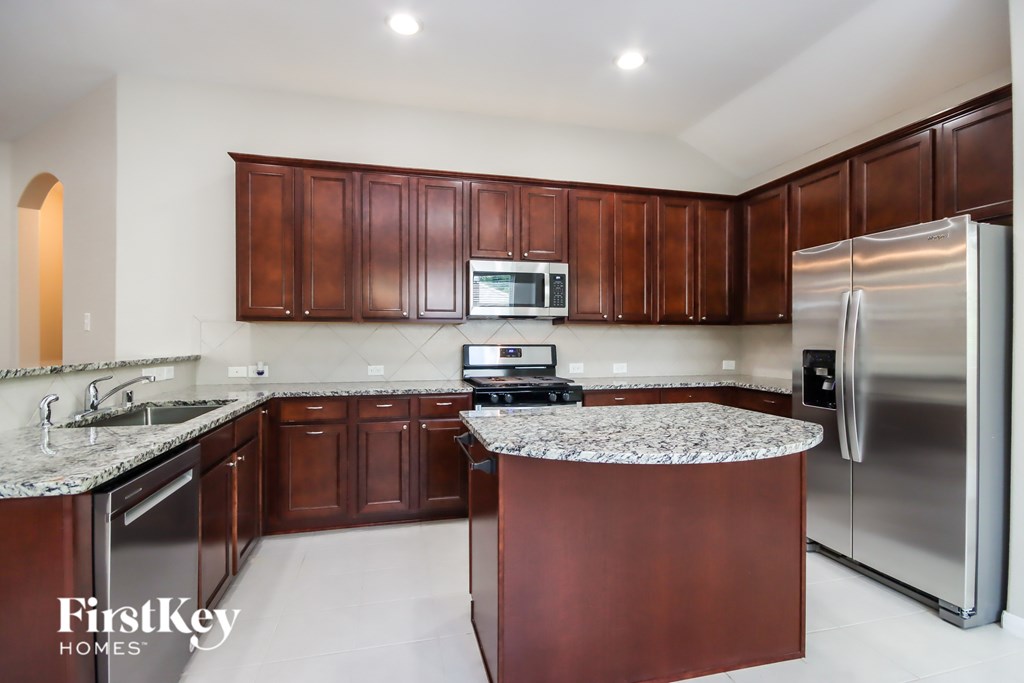 A kitchen with brown cabinets and a granite countertop.