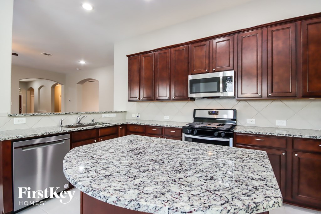 A kitchen with a granite countertop and wooden cabinets.