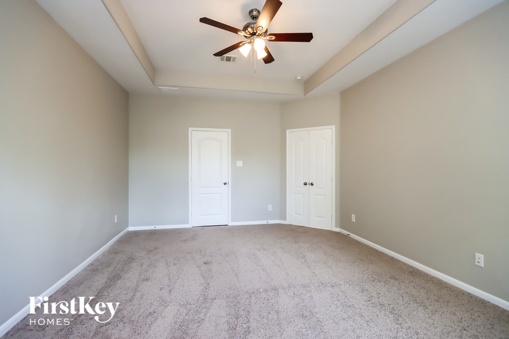 A room with a ceiling fan and two doors.