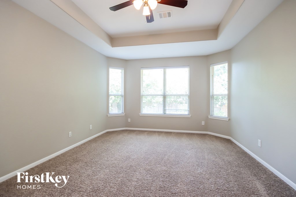 A spacious room with a carpeted floor and a ceiling fan.