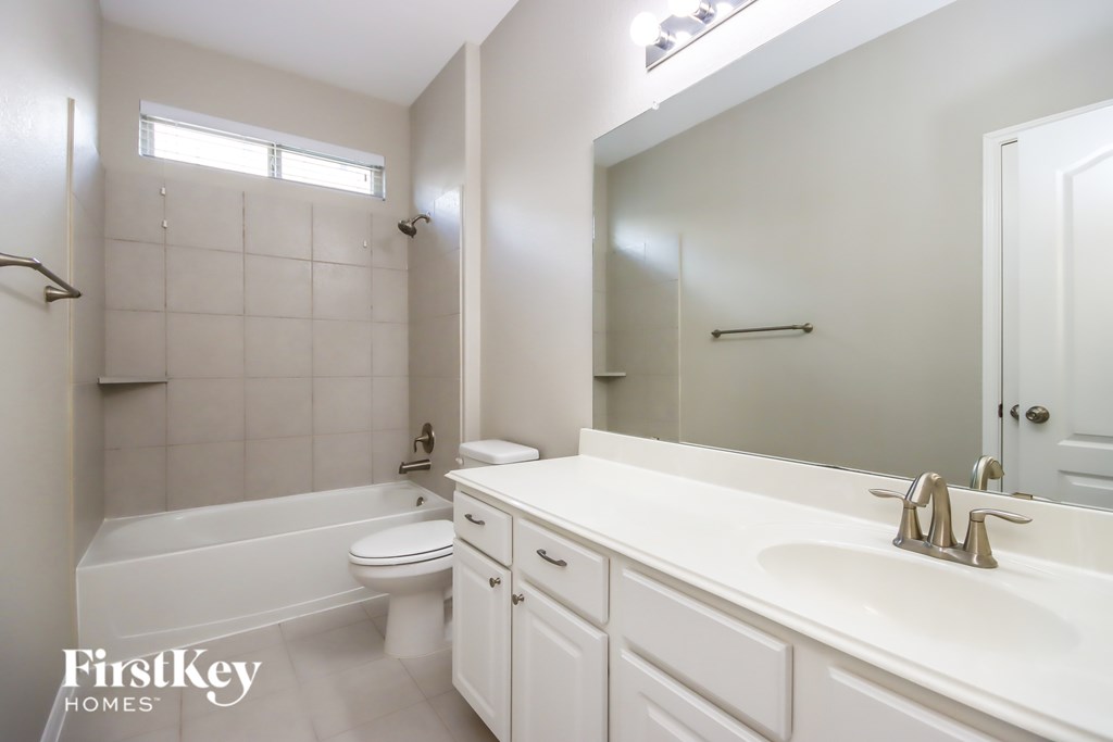A white bathroom with a tub, toilet and sink.