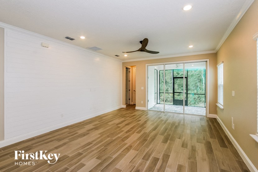 A spacious room with wooden flooring and a ceiling fan.