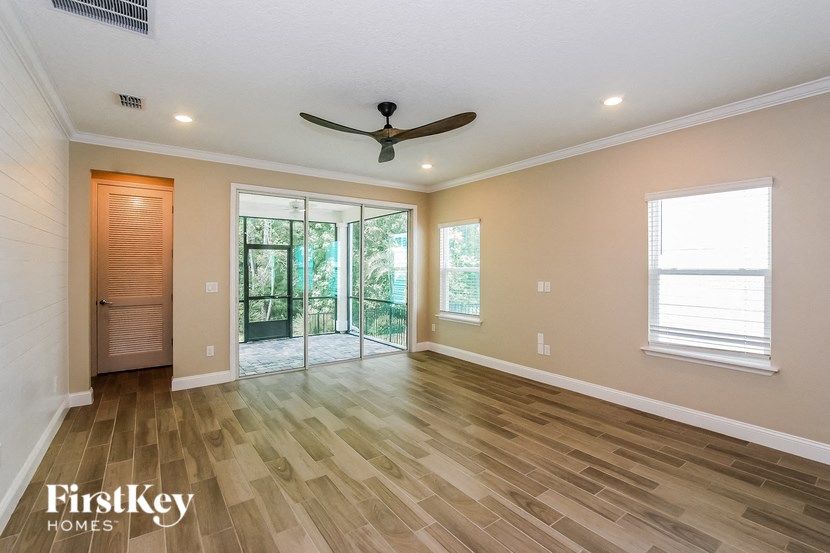 A spacious room with wooden flooring and a ceiling fan.