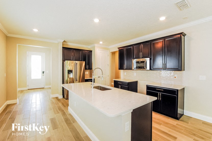 A kitchen with a white island and black cabinets.