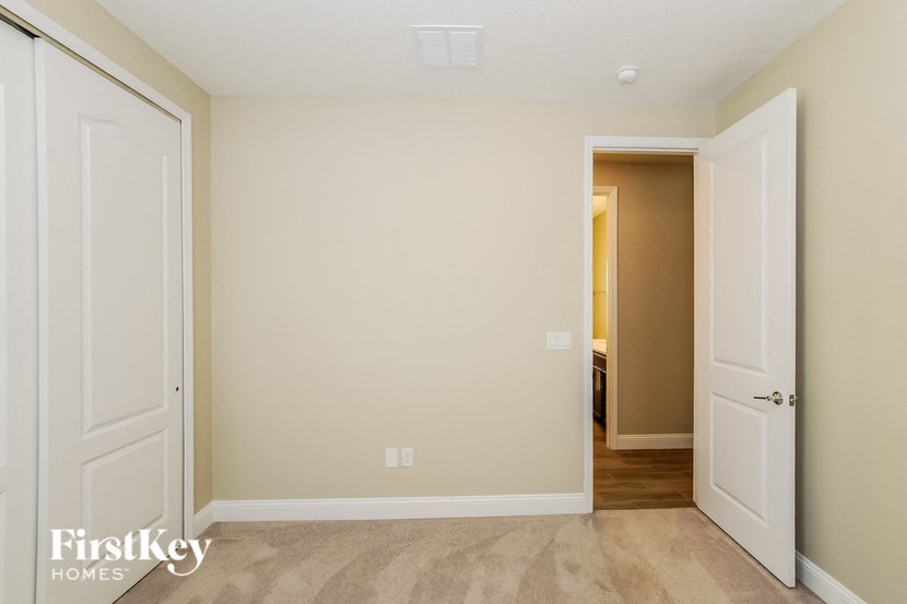 A room with a carpeted floor and two doors.