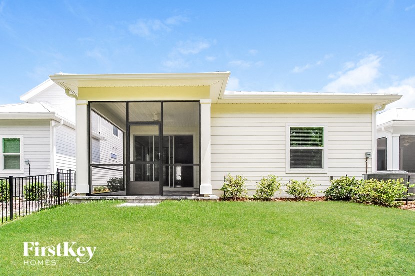 A white house with a black fence and a green lawn.
