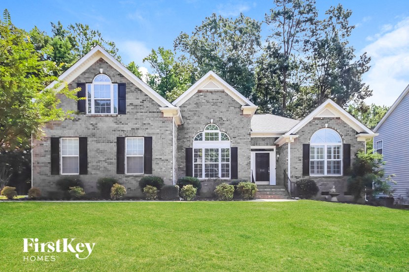 a stone house with black shutters and a green lawn