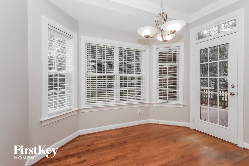 a living room with a hardwood floor and a door to a balcony