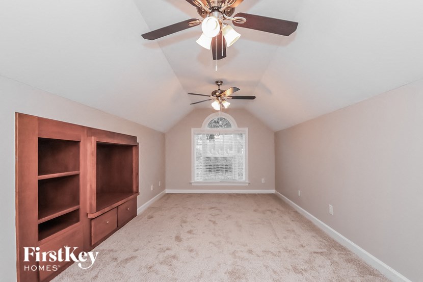 a empty bedroom with a ceiling fan and a window