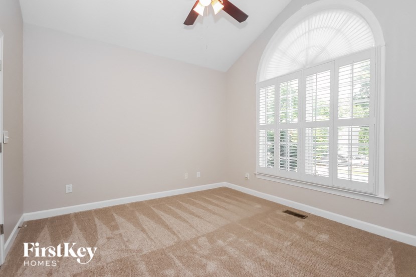 an empty living room with a large window and a ceiling fan